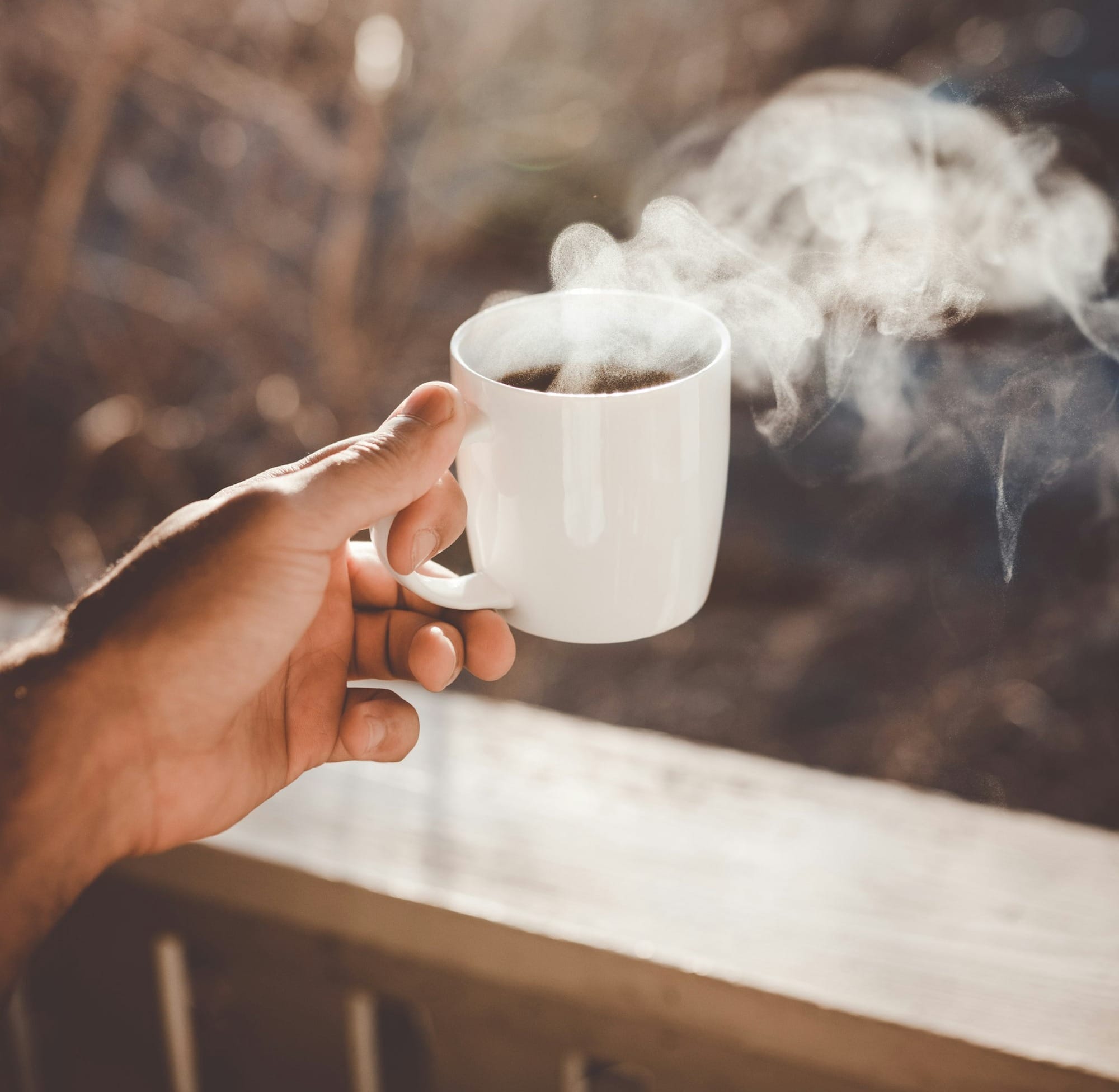 person holding white ceramic cup with hot coffee